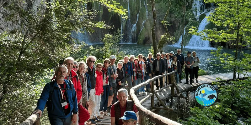 Visitors on a boardwalk beside a waterfall on a guided walking Plitvice Lakes National Park tour, Croatia